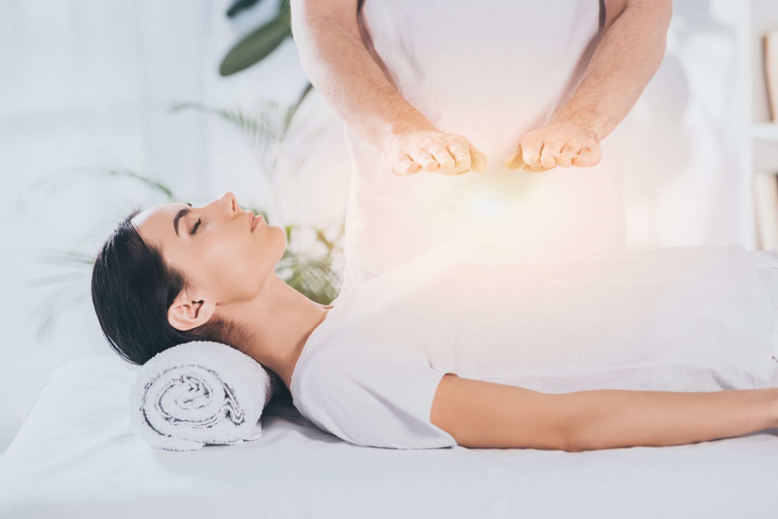 Healing hands hovering over a woman on massage table